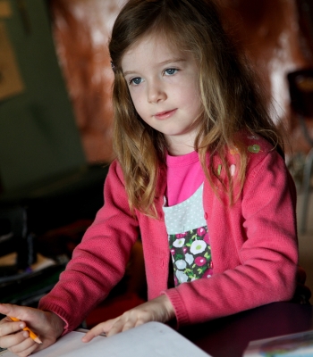 Button to Apply to Oak and Orca School, Child Writing at Desk